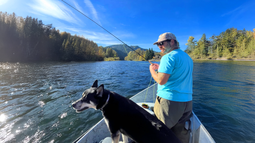 Fly fisherman casting line from drift boat with dog during Oregon fly fishing trip