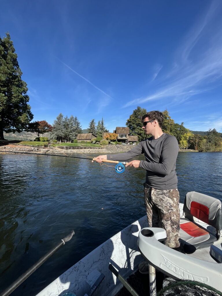 Fisherman casting fly rod along scenic Oregon fly fishing river